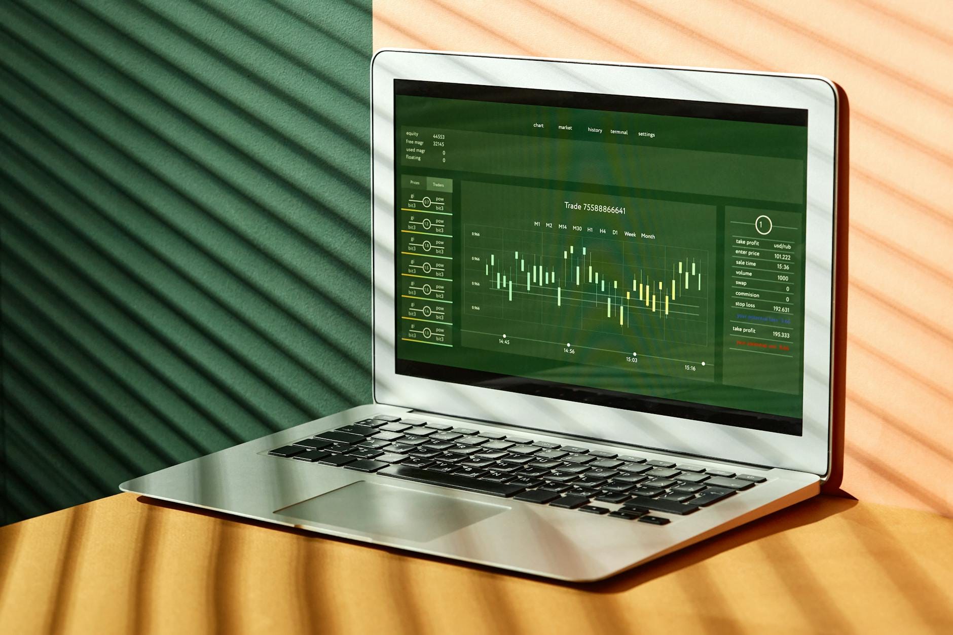 A laptop displaying stock market data with shadows from window blinds casting dramatic patterns.